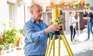 Land surveyor using total station - ALTA SURVEY Minnesota Land surveyor setting up a total station to verify property boundaries for an ALTA Land Title Survey before construction