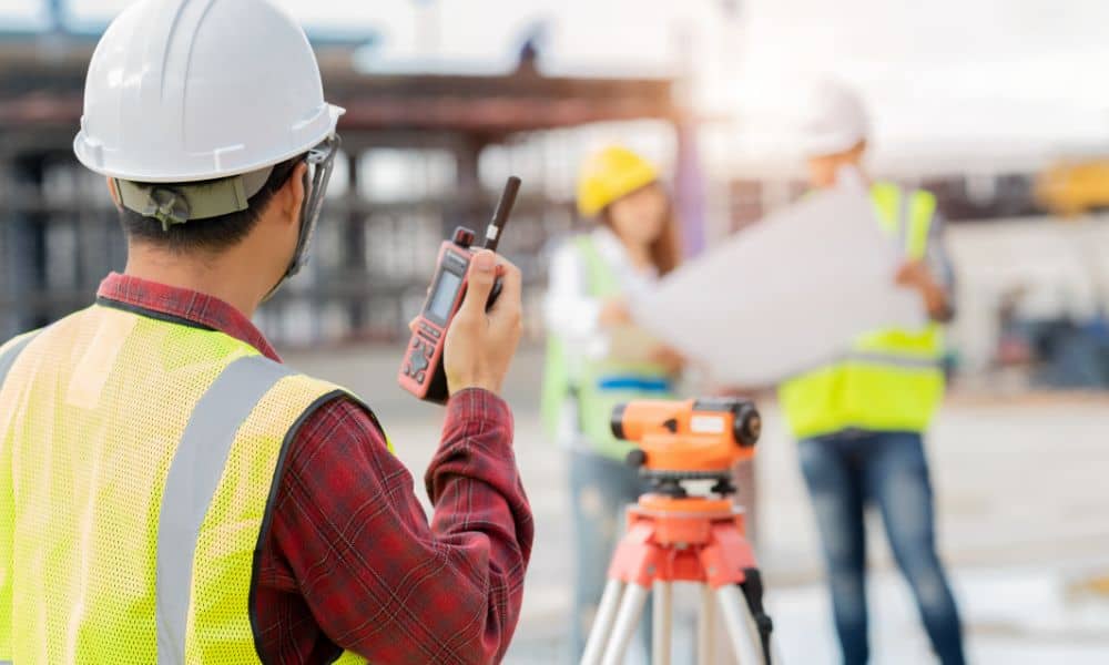 Licensed land surveyor performing an alta survey using a total station at a commercial property site