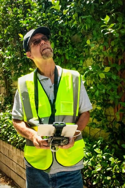 Land surveyor operating a drone controller during a site assessment to capture aerial data for redevelopment projects
