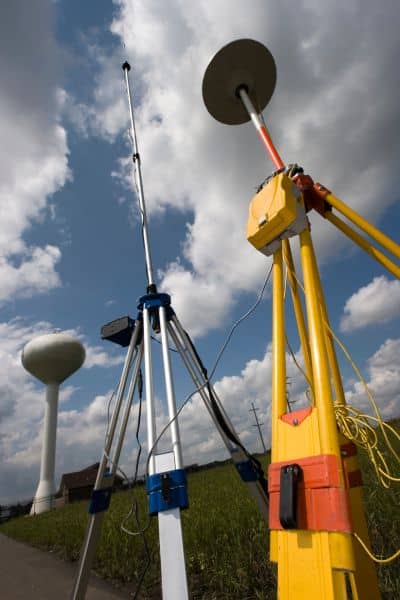 Land surveying GPS base station equipment set up in the field under cloudy sky

