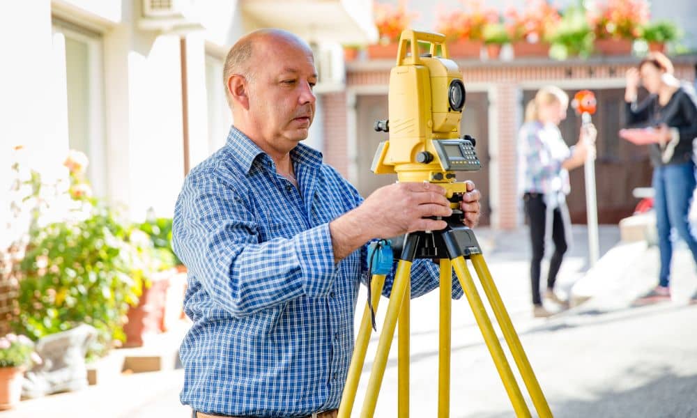 Land surveyor setting up a total station to verify property boundaries for an ALTA Land Title Survey before construction