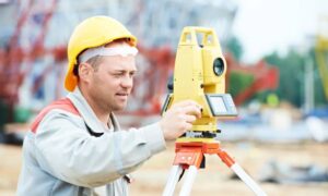 Licensed land surveyor using a total station at a construction site, symbolizing the shift from traditional fieldwork to digital surveying