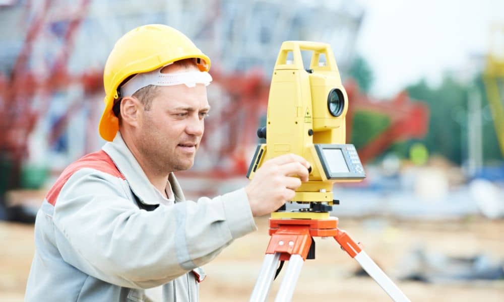 Licensed land surveyor working on construction site - ALTA SURVEY Minnesota Licensed land surveyor using a total station at a construction site, symbolizing the shift from traditional fieldwork to digital surveying