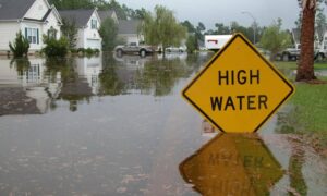 Flooded residential street with a high water sign, showing why homeowners may need an elevation certificate to understand their property’s risk