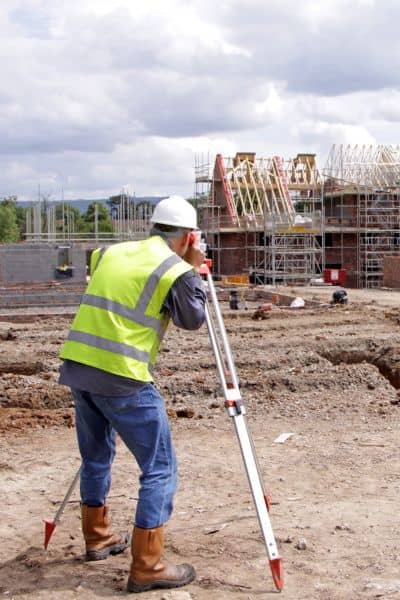 Land surveyor using leveling equipment to collect accurate data that supports an elevation certificate for homeowners