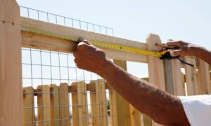 Homeowner measuring fence installation while planning improvements and considering land survey cost