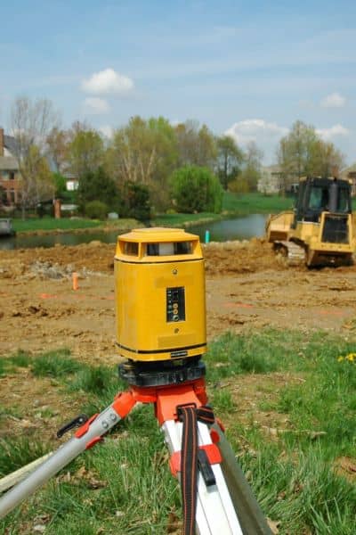 Professional surveyor on lot - ALTA SURVEY Minnesota Licensed surveyor using equipment to perform a property line survey on a residential lot