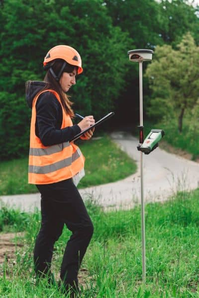 Professional surveyor using GPS equipment to measure property boundaries and calculate land survey cost
