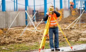 Construction surveyor using a total station to verify layout on a job site