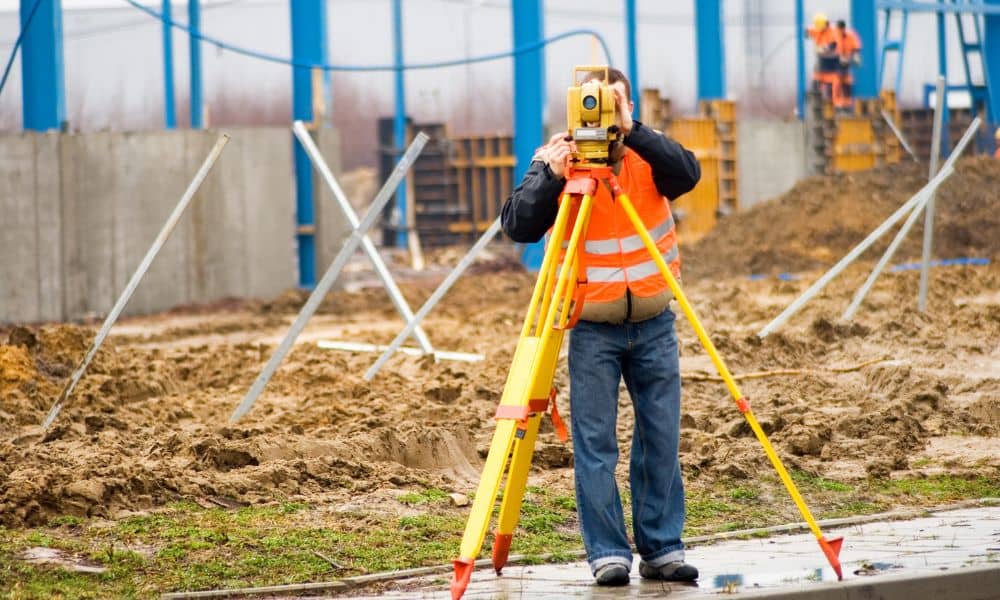 Construction surveyor using a total station to verify layout on a job site