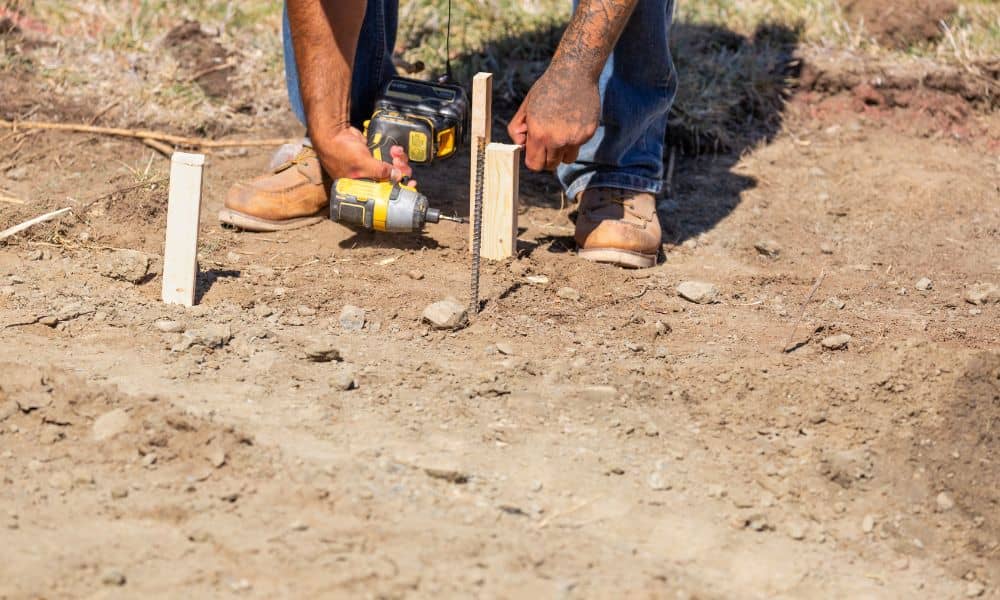  A surveyor marking property lines during a boundary survey on a dirt lot