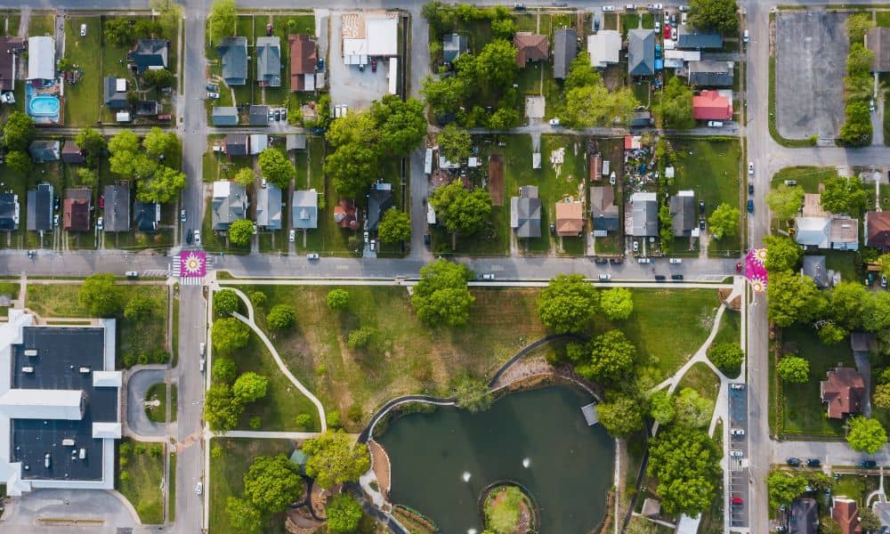Aerial view of a neighborhood with roads, green spaces, and a pond used to illustrate survey mapping for stormwater planning